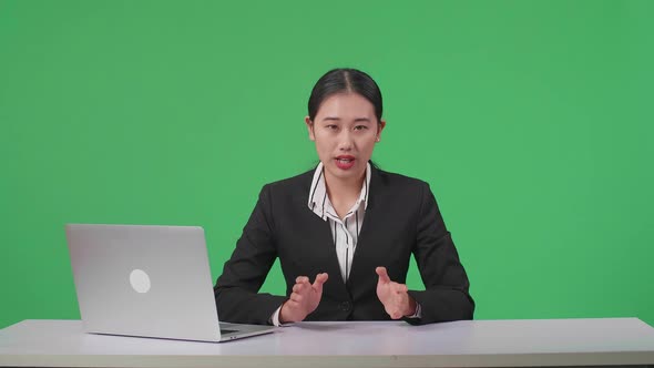 Live News Studio With Asian Female Anchor And Her Computer Reporting On The Events On Green Screen