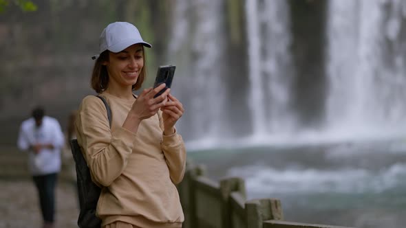 Attractive Smiling Woman Tourist Making Selfie on Mobile Phone on Lower Duden Waterfall Background