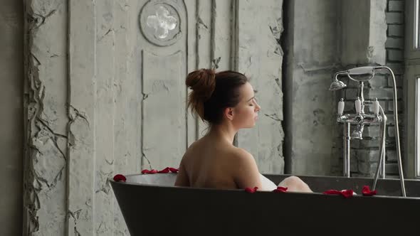 Girl Lies in a Large Stone Bath in Foam