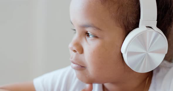 Afro American Kid Girl School Pupil Wearing Headphones Studying Online From Home Watching Web Class