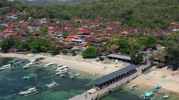 local fishing village at Padangbai port in Bali Indonesia with tourists on pier, aerial