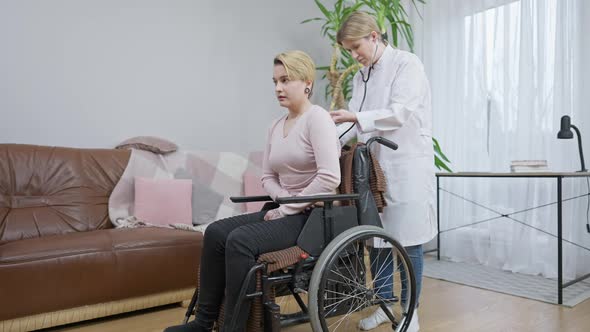 Wide Shot of Focused Female Doctor Using Stethoscope As Disabled Caucasian Patient Breathing in and