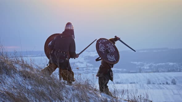 Two Viking Are Fighting with Axes and Shields on The Winter Meadow.