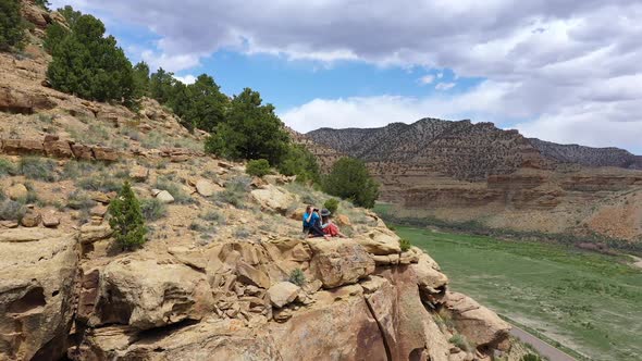 Two women sitting on edge of cliff looking over the valley