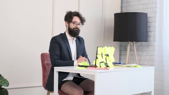 Bearded Man Comfortable at His Desk in Underwear and Jacket Working Remote