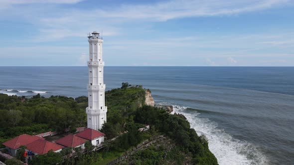 Aerial view of Baron Beach in Gunung Kidul, Indonesia with lighthouse and traditional boat.