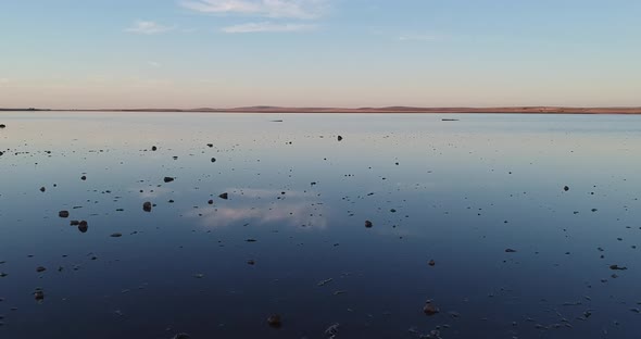 Flying low over the pink lake and Lochiel in South Australia, with rocks on the edge of the water le