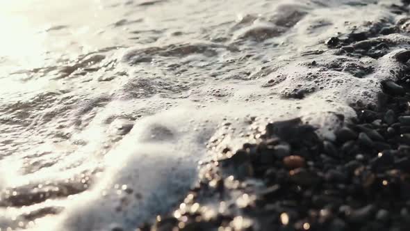 Sea Waves Are Washing Gravel Beach, Close-up in Sunset Time