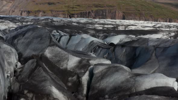 Low Flight Above Melting Valley Glacier Covered By Layer of Black Volcanic Ash