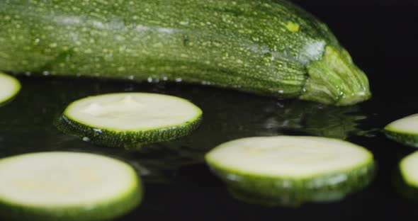 Slices of Fresh Zucchini Fall To the Water with a Splash. 