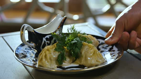 Closeup Person Puts Plate with Tatar Dumplings on Table