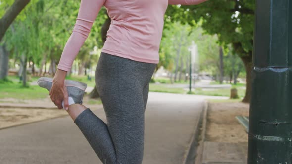 Senior woman stretching her legs in the park