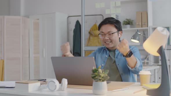 Cheerful Asian Office Worker Typing on Laptop and Getting Excited