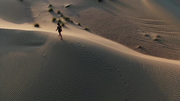 Aerial Footage of a Young Lady Walking in the Desert on a Sand Dune UAE