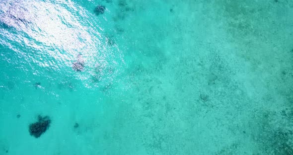 Daytime aerial clean view of a white sandy paradise beach and aqua blue water background in colorful