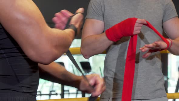 Cropped Shot of Two Male Boxers Wrapping Fists in Bandages Before Fighting