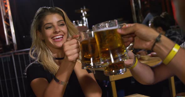 Group of friends toasting beer mugs at a concert 4k