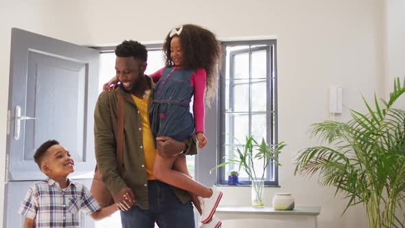 Happy african american father coming back home and hugging with children