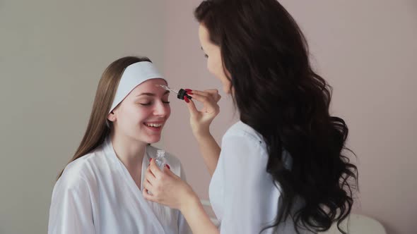 Cosmetologist Applies Peeling Lotion on Woman Client Face in Beauty Clinic Salon