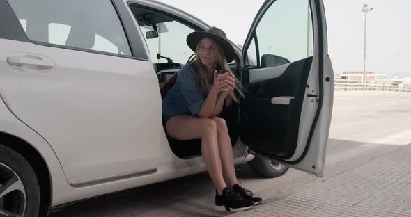 Tourist woman during roadtrip taking a break with coffee in car on the road side