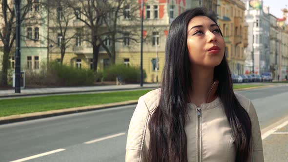 A Young Asian Woman Looks Around in a Street in an Urban Area