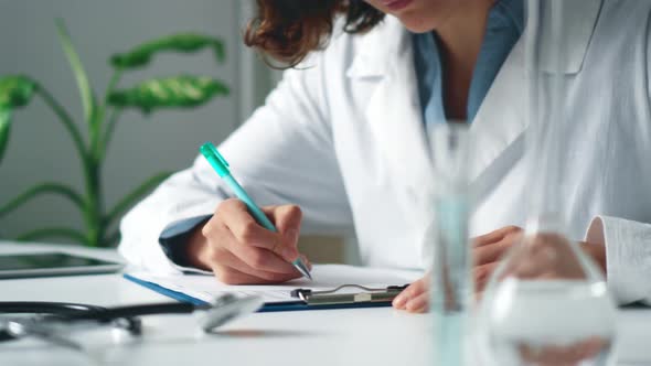 Young Female Doctor Working In The Office Clinician In White Coat Fills Out Medical Forms On Tablet