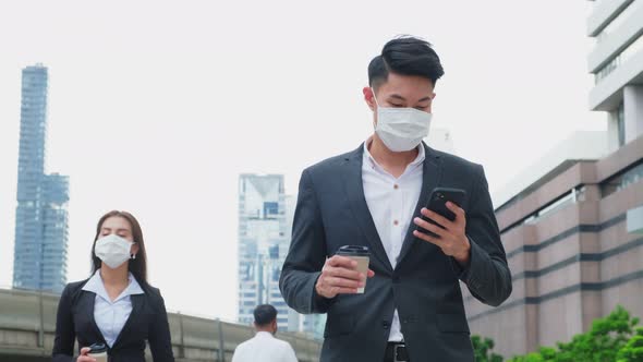 Group of young office businesspeople wear mask, use phone and walk outdoor in city with new normal.