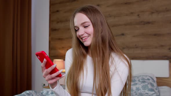 Girl Looks at Screen of Mobile Smartphone Makes Successful Online Order Smiles and Looks at Camera