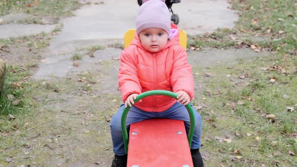 Cheerful toddler girl playing at children playground. Slow motion.