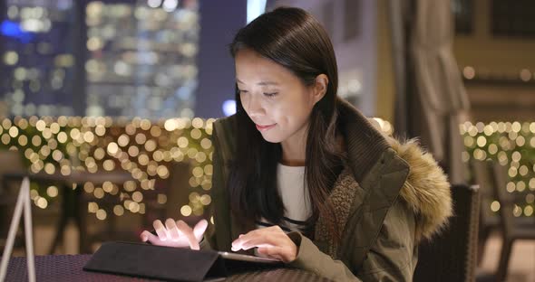 Woman use of tablet computer in coffee shop at night