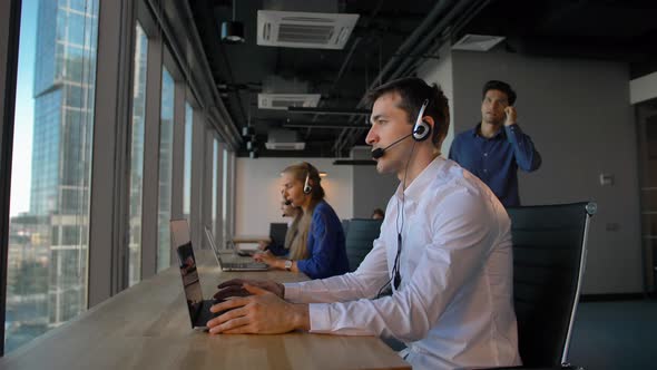 Call Center Employee in Office Talking with Client and Then Smile To Camera