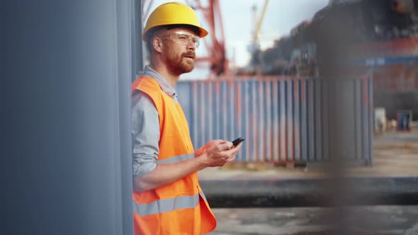 Man shipbuilder in uniform texting by phone