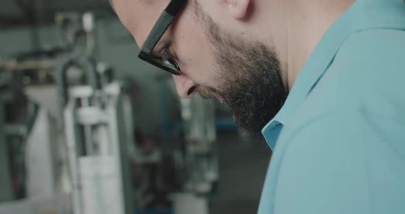 Close Profile Portrait of Engineer in Glasses During Work on Factory at Machine