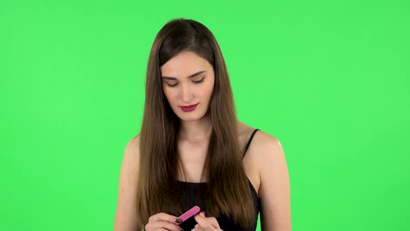 Girl Makes Herself Manicure with Pink Nail File. Green Screen