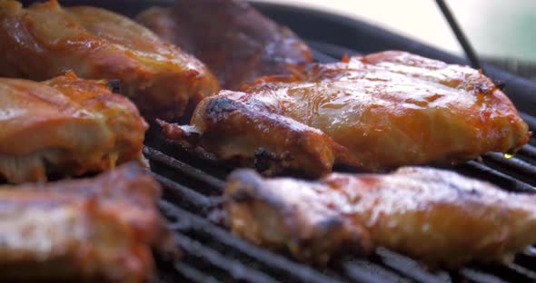 Lemon seasoned chicken cooks on the grill in the backyard.