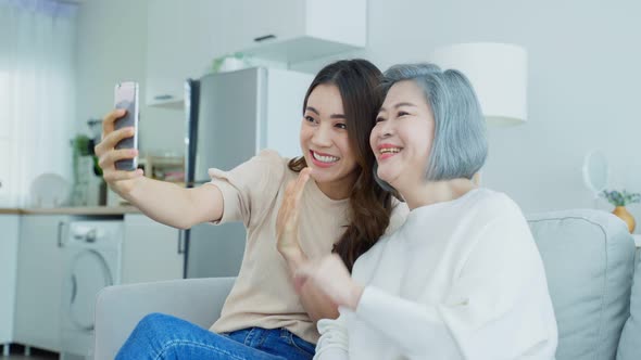 Asian lovely family, young daughter use phone selfie with older mother.