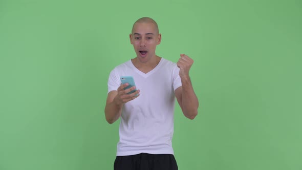 Happy Handsome Bald Man Using Phone and Looking Surprised