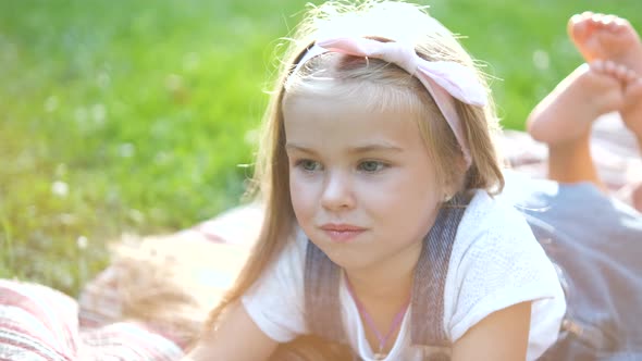 Portrait of Pretty Child Girl Resting Outdoors in Summer Park