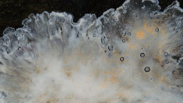 White Paint Spreads on a Black Goldglittering Moving Background