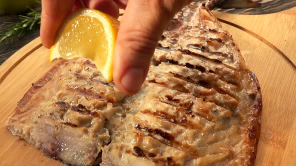 Hand is Squeezing Slowly a Lemon Juice on the Grilled White Mackerel Fish Fillet