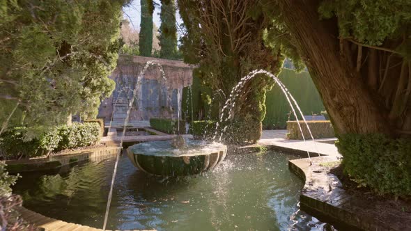 Slow Motion Gimbal Shot of Fountain Surrounded By Trees in Gardens of the Generalife in Alhambra