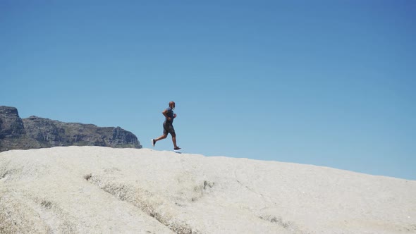 Senior african american man exercising running on rocks by the sea