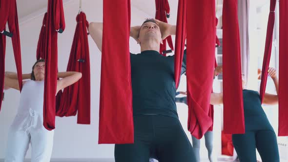 Group Puts Hands Behind Head Relaxes in Fly Yoga Hammocks