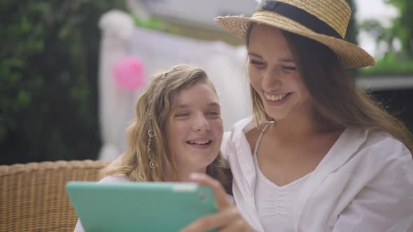 Portrait of Young Woman and Teenage Girl Gossiping Surfing Social Media on Tablet Outdoors