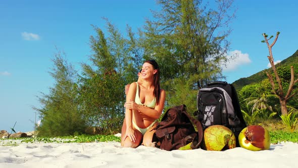 Young happy ladies on photoshoot spending quality time at the beach on sunny blue and white sand bac