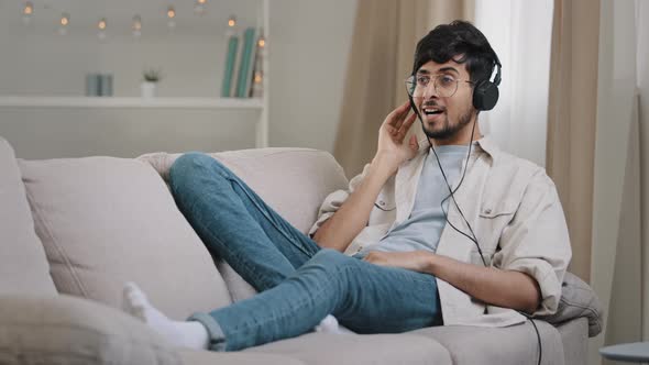 Young Cheerful Active Hispanic Guy Having Fun Bearded Arabian Man Lying on Couch at Home in