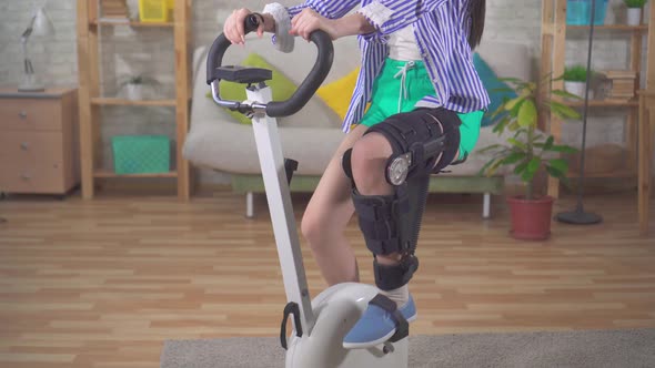 Portrait Asian Woman Knee Bend Orthosis Knee Brace After Injury on a Stationary Bike Knee Bend