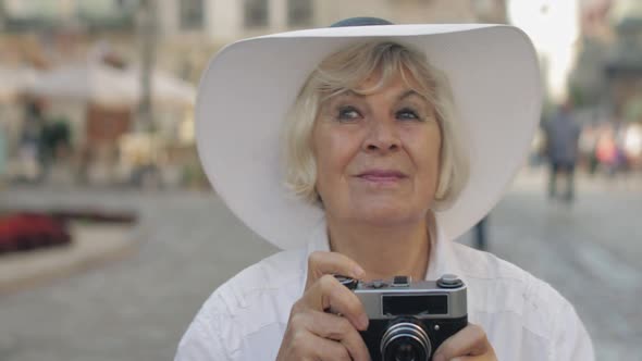 Senior Female Tourist Exploring Town and Makes a Photo with Retro Photo Camera