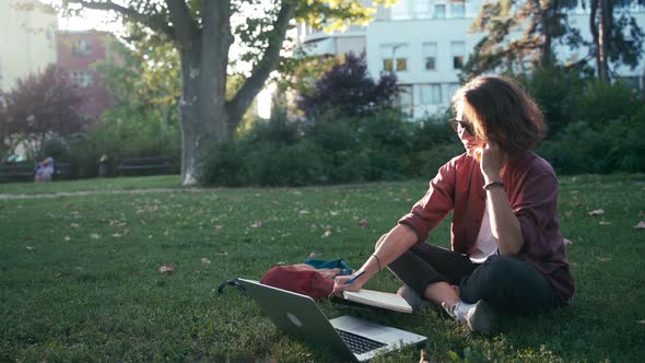 Young Student Girl Making Notes in Her Notebook and Taking a Phone Call