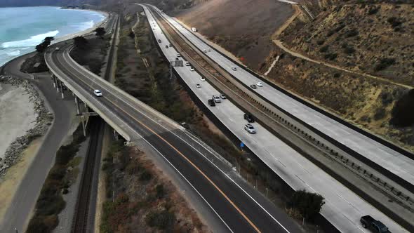 Aerial drone shot over the top of a concrete bridge on the beach in Ventura next to the ocean waves